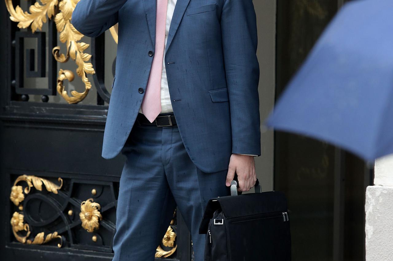 28.04.2016., Zagreb - Ministar Tomislav Tolusic nakon izlaska iz Sabora pokusao je telefonom locirati vozaca i na kraju na kisu otisao pjesice. Photo: Patrik Macek/PIXSELL