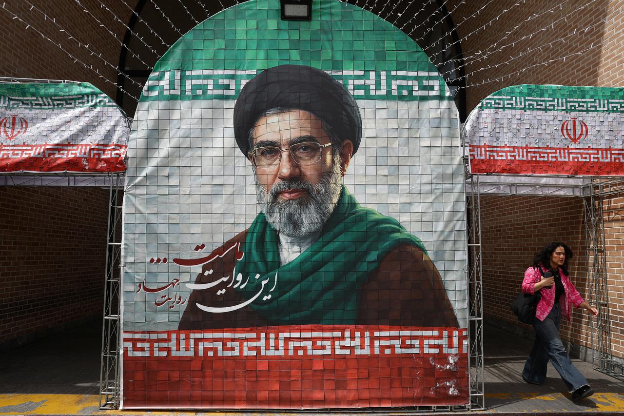 A woman walks next to a banner with a picture of Iran's new Supreme Leader Mojtaba Khamenei in Tehran