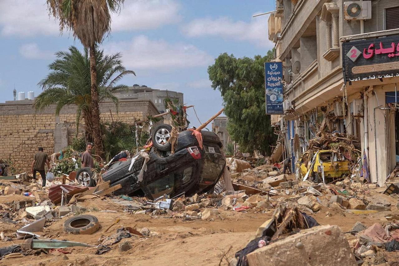 A man stands next to a damaged car, after a powerful storm and heavy rainfall hit Libya, in Derna