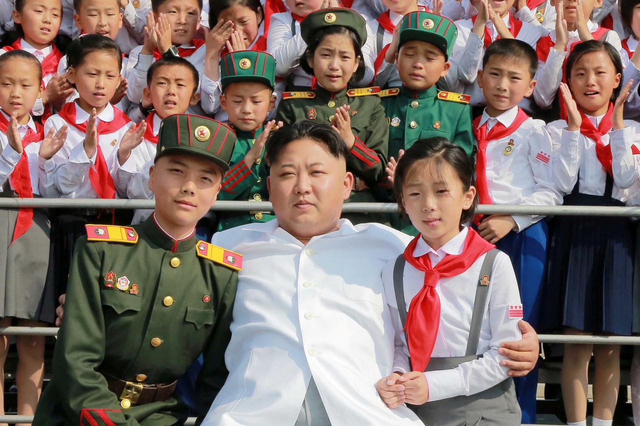 FILE PHOTO - Schoolchildren stand beside North Korean leader Kim Jong Un as he arrives to attend 