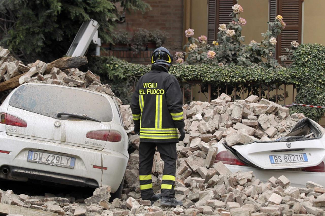 'A firefighter stands next to damaged cars after an earthquake in Finale Emilia May 20, 2012. A strong earthquake rocked a large swathe of northern Italy early on Sunday, killing at least three people