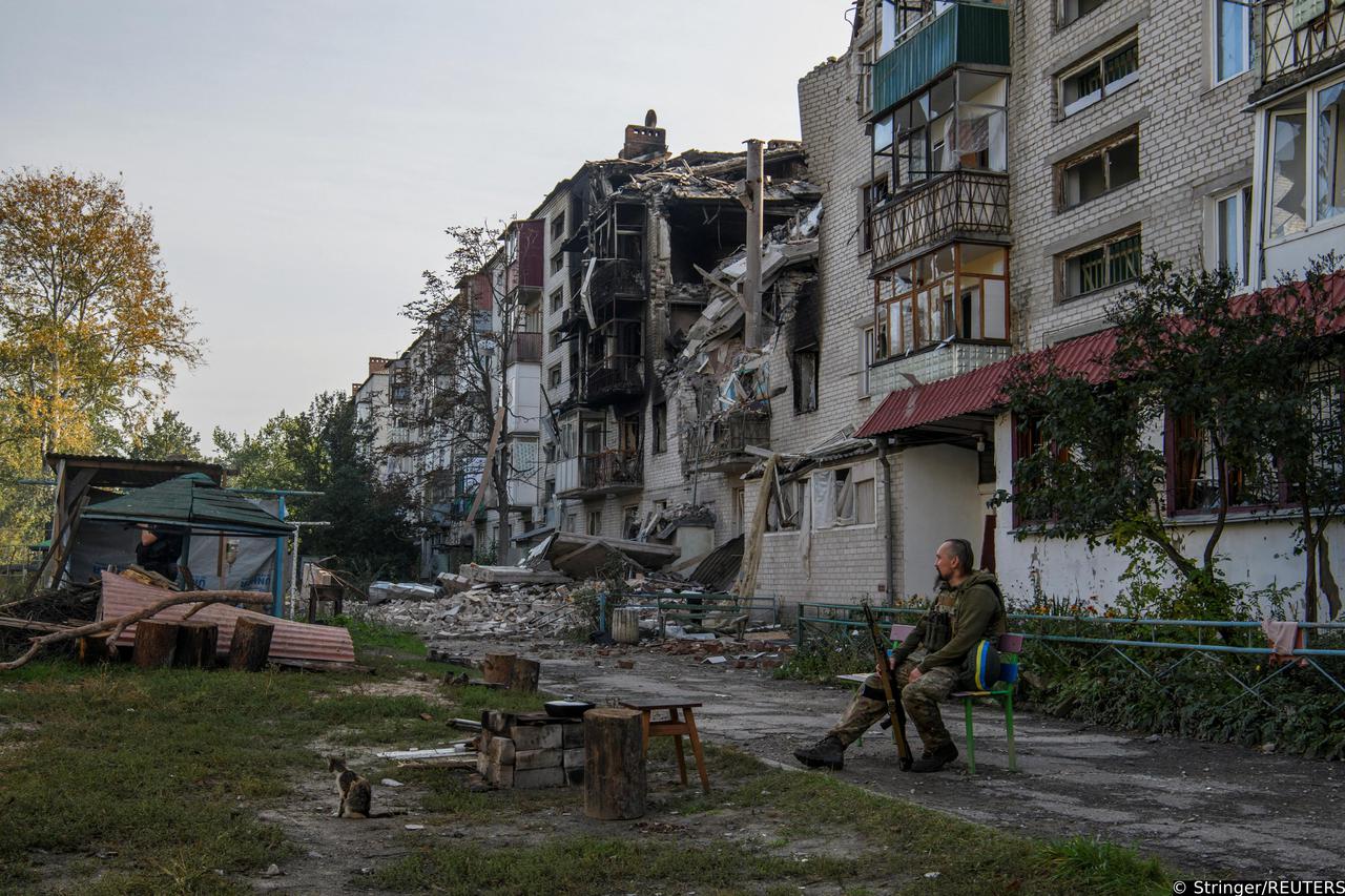 Ukrainian service member list on a bench near a destroyed residential building in the town of Sviatohirsk