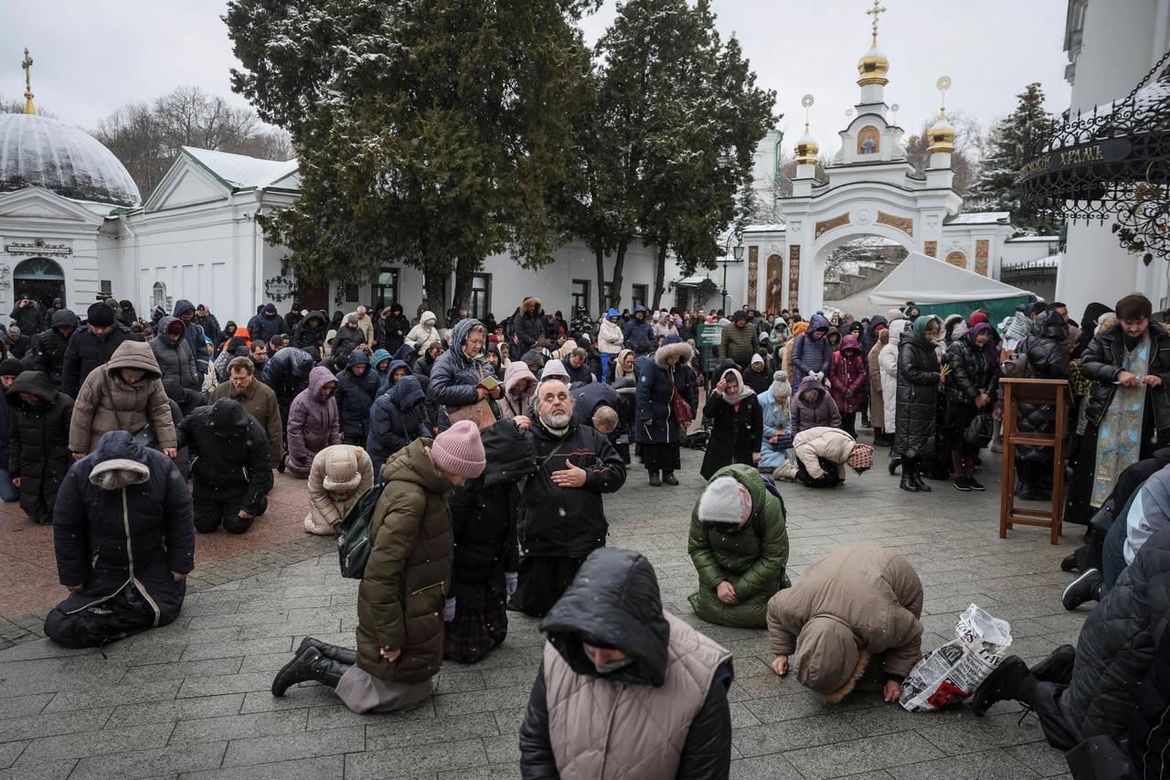 Believers pray outside a church during a service at a compound of the Kyiv Pechersk Lavra monastery in Kyiv