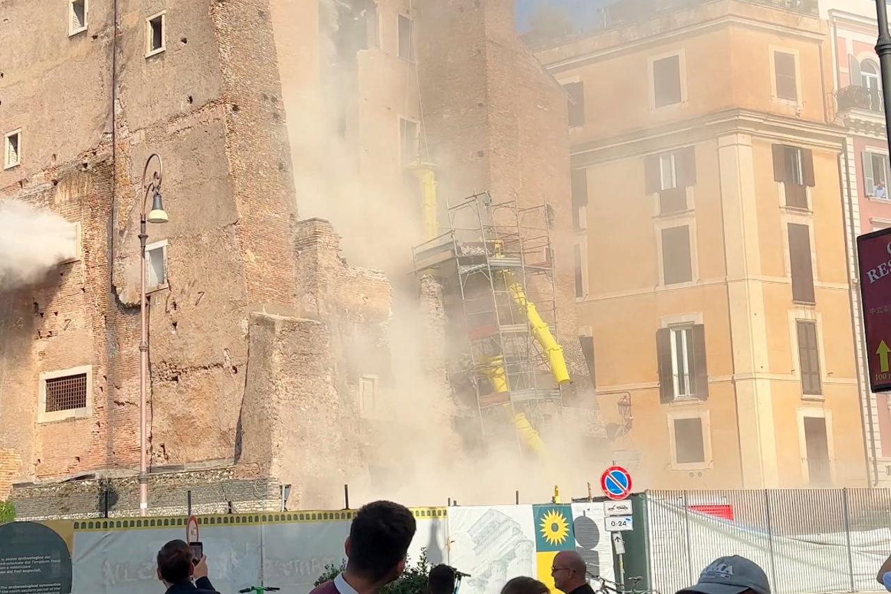 Onlookers watch as dust rises from the Torre dei Conti following a partial collapse, in Rome
