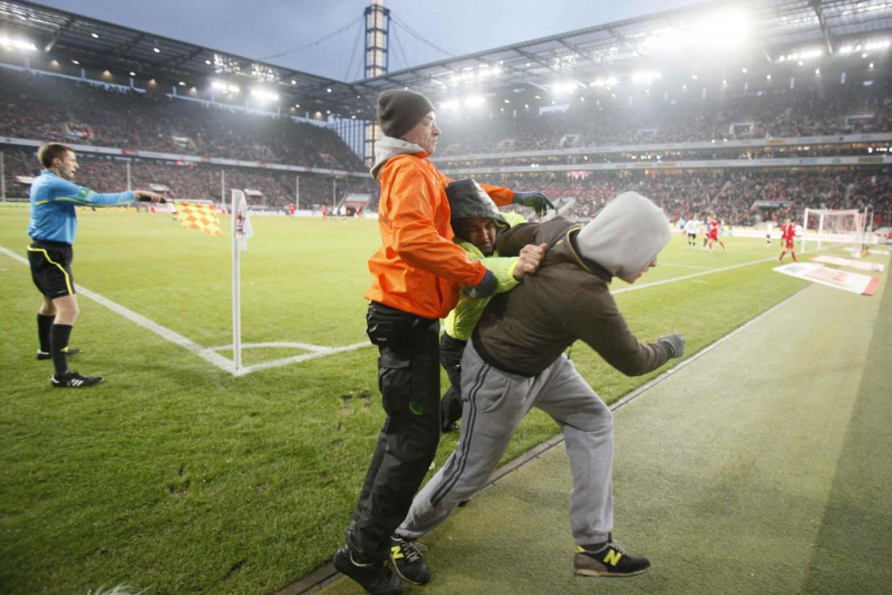 \'Security staff try to remove an unruly supporter of Eintracht Frankfurt  from the sidelines during his team\'s German first division Bundesliga soccer match against FC Cologne in Cologne December 11