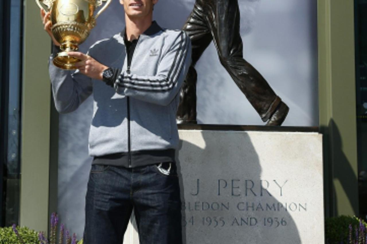 'Tennis player Andy Murray of Britain holds the trophy under a statue of former British champion Fred Perry, at Wimbledon, southwest London July 8, 2013. Murray wiped out 77 years of pain when he beca
