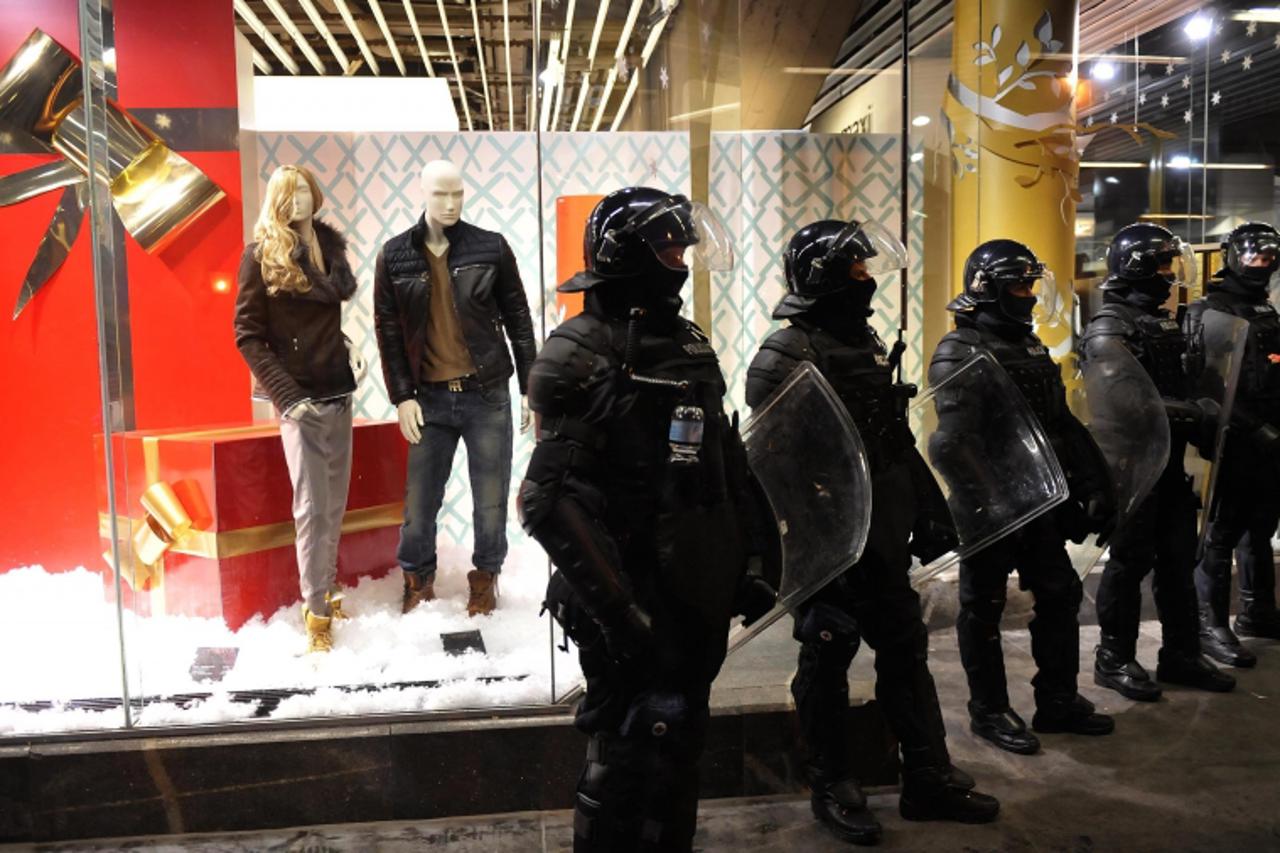 'Riot police officers, deployed as part of heightened security measures against demonstrations over budget cuts and alleged corruption, stand guard near a shop window with Christmas decorations in Lju