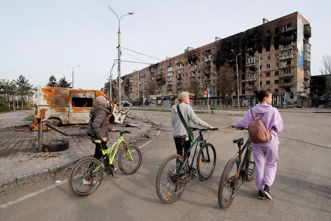 People look at a damaged residential building in Mariupol