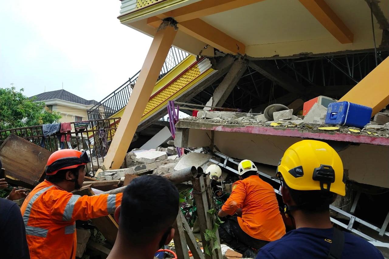 Members of a search and rescue agency team dig through rubble after an earthquake, in Mamuju