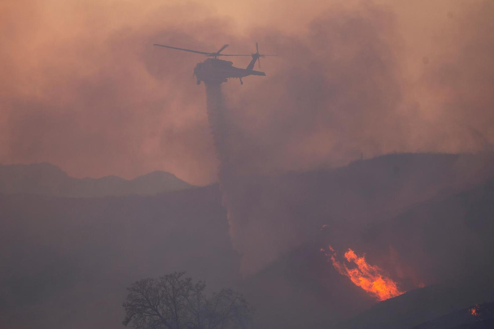 A helicopter drops water, as firefighters and aircraft battle the Hughes Fire near Castaic Lake, north of Santa Clarita, California, U.S. January 22, 2025.  REUTERS/Ringo Chiu Photo: RINGO CHIU/REUTERS