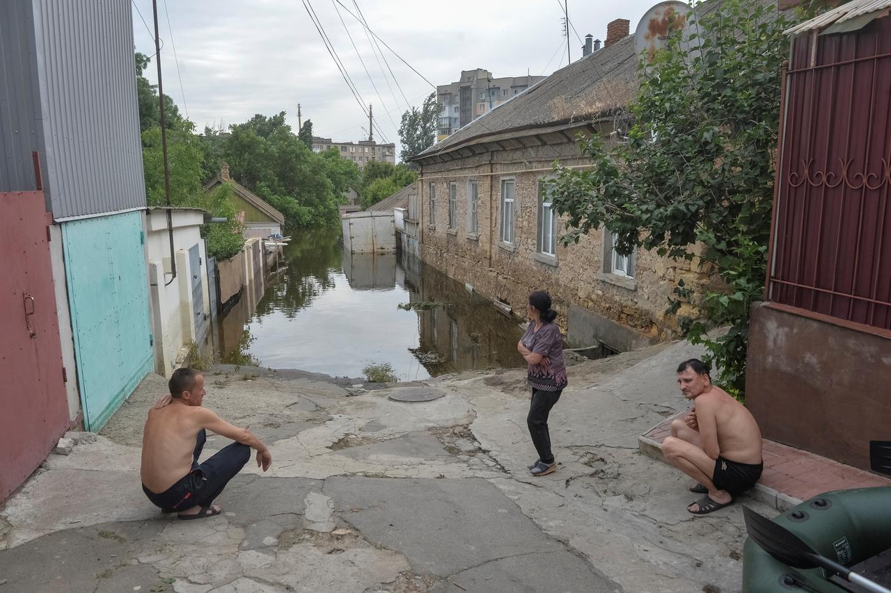 Local residents are seen near a flooded area after the Nova Kakhovka dam breached in Kherson