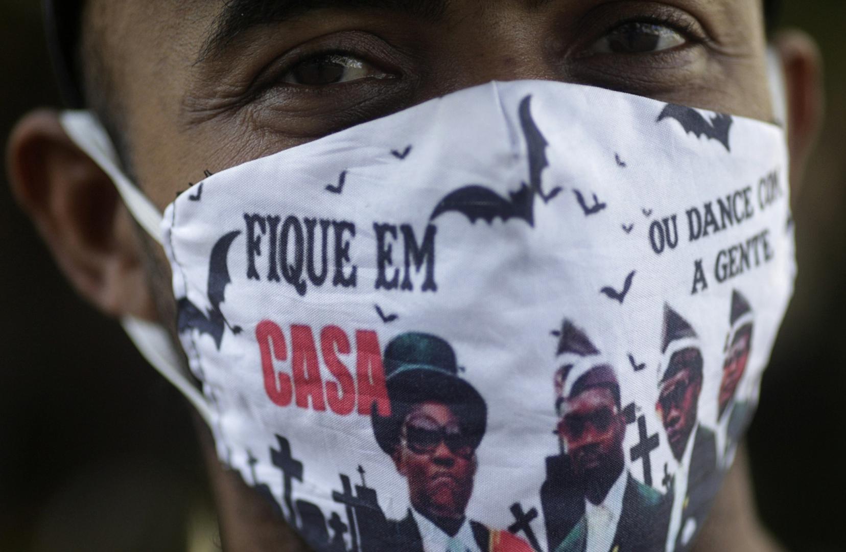 Outbreak of the coronavirus disease (COVID-19) in Rio de Janeiro A man wears a protective face mask with a picture of the Ghana's dancing pallbearers, that reads "Stay at home, or dance with us" as he waits outside a public bank, where most of people try to receive emergency aid given by the federal government to the most vulnerable, during the coronavirus disease (COVID-19) outbreak, in Rio de Janeiro, Brazil, May 29, 2020. REUTERS/Ricardo Moraes RICARDO MORAES