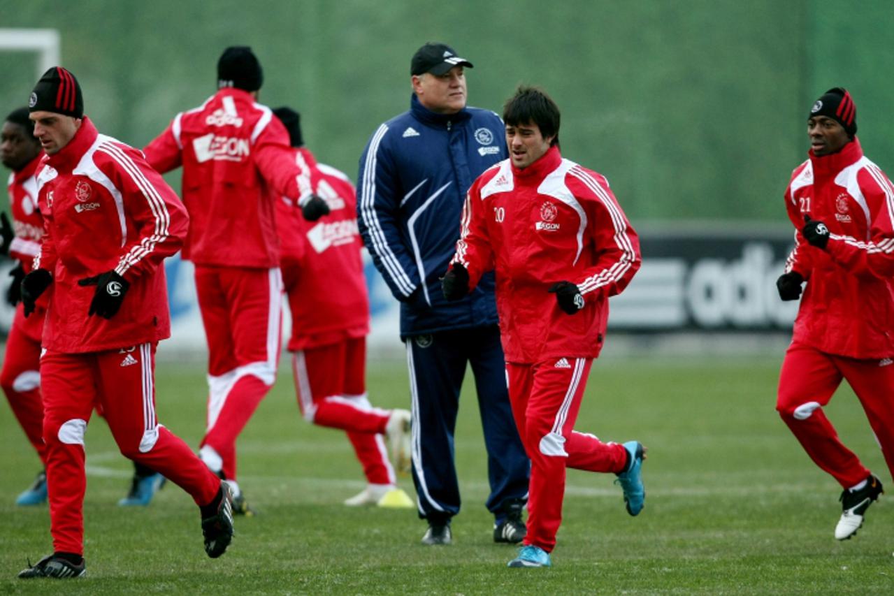 'Ajax players  Bruno Silva (L) , Dario Cvitanich (2-R) and Eyong Enoh (R) perform warming up exercises as coach MartIn Jol (3-R) looks on during a training session in Amsterdam on December 16, 2009. A