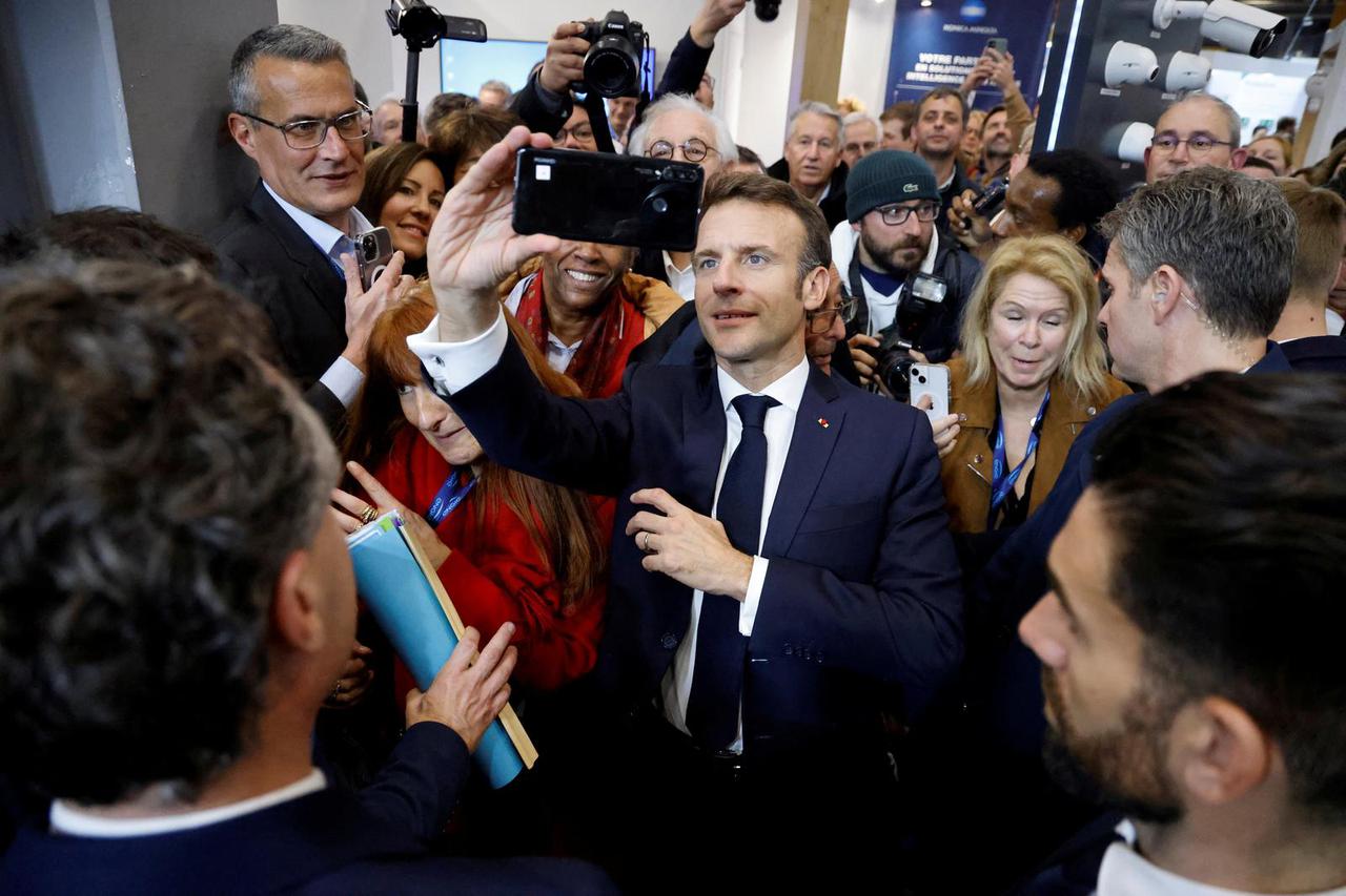 France's President Emmanuel Macron takes a selfie with a visitor during the 104th session of the Congress of Mayors in Paris