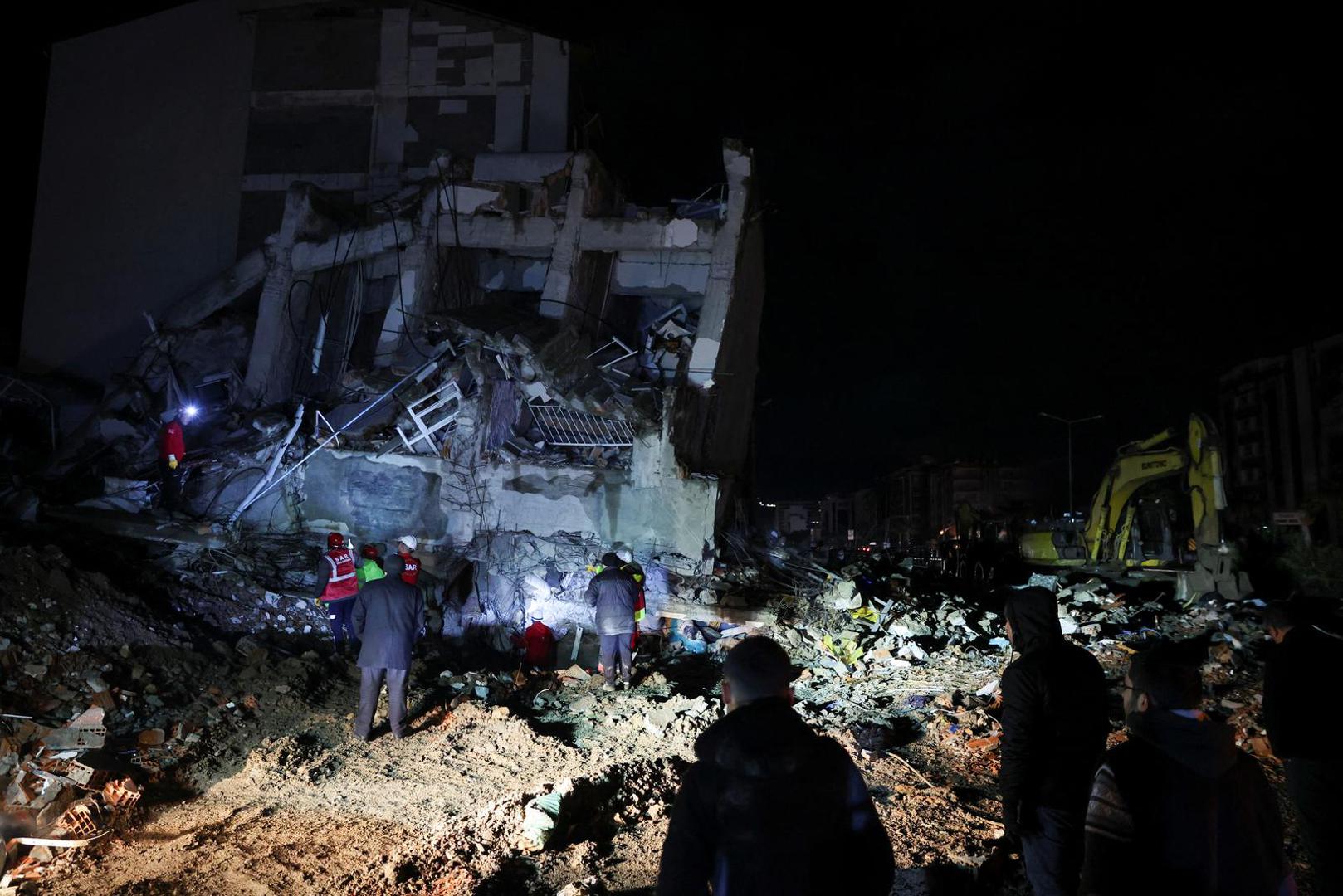 People look at a collapsed building as rescue team work at the site, following an earthquake in Iskenderun, Turkey February 6, 2023. REUTERS/Umit Bektas Photo: UMIT BEKTAS/REUTERS