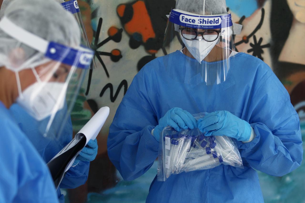 A health worker wearing personal protective equipment  holds a bag with test tubes in a school following the easing of lockdown measures against the spread of the coronavirus disease (COVID-19) on the education sector