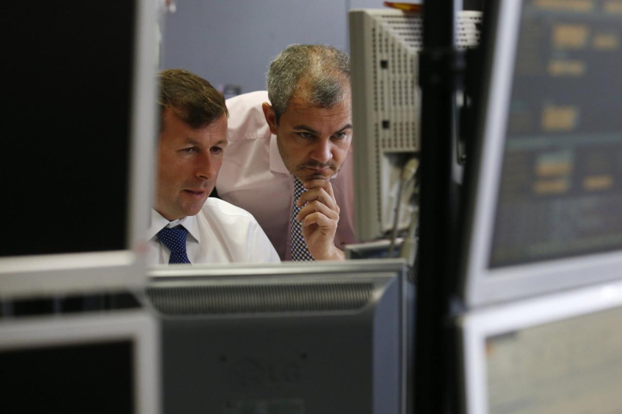 'Traders look at computer screens during a Spanish bond auction in Madrid October 18, 2012. Spain sold more debt than it planned and its funding costs fell on Thursday after Moody's affirmed its cred
