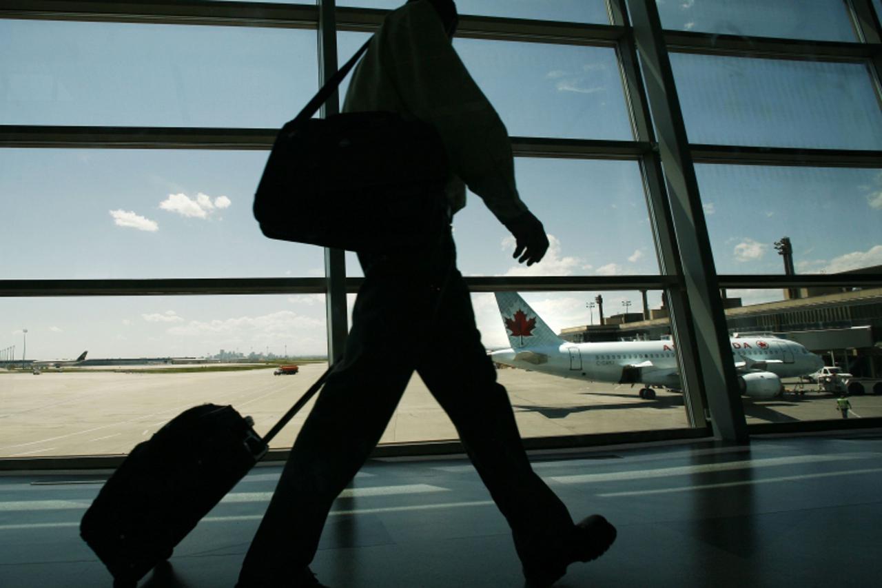 'An Air Canada passenger walks to catch his plane at the Calgary International Airport in Calgary, Alberta, June 17, 2008. Air Canada will cut 2,000 jobs and shrink its capacity by 7 percent as runawa