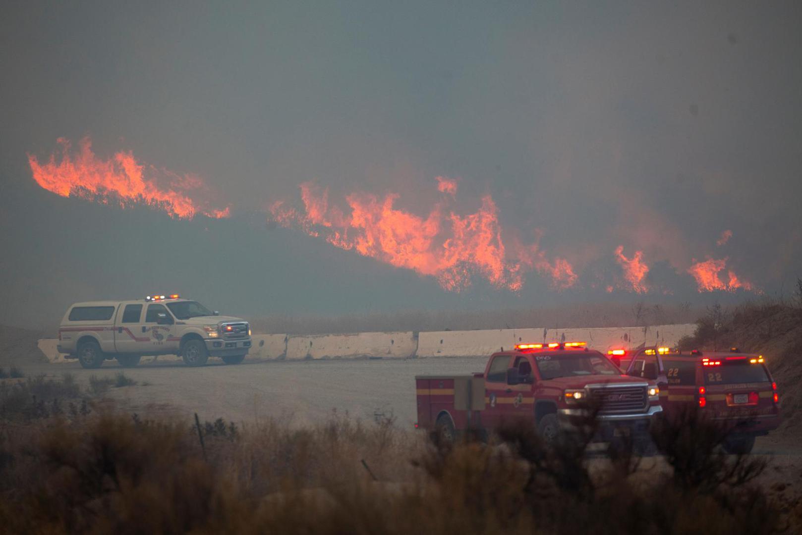 Flames rise in the background, behind an emergency services vehicle, as firefighters and aircraft battle the Hughes Fire near Castaic Lake, north of Santa Clarita, California, U.S. January 22, 2025. REUTERS/Ringo Chiu Photo: RINGO CHIU/REUTERS