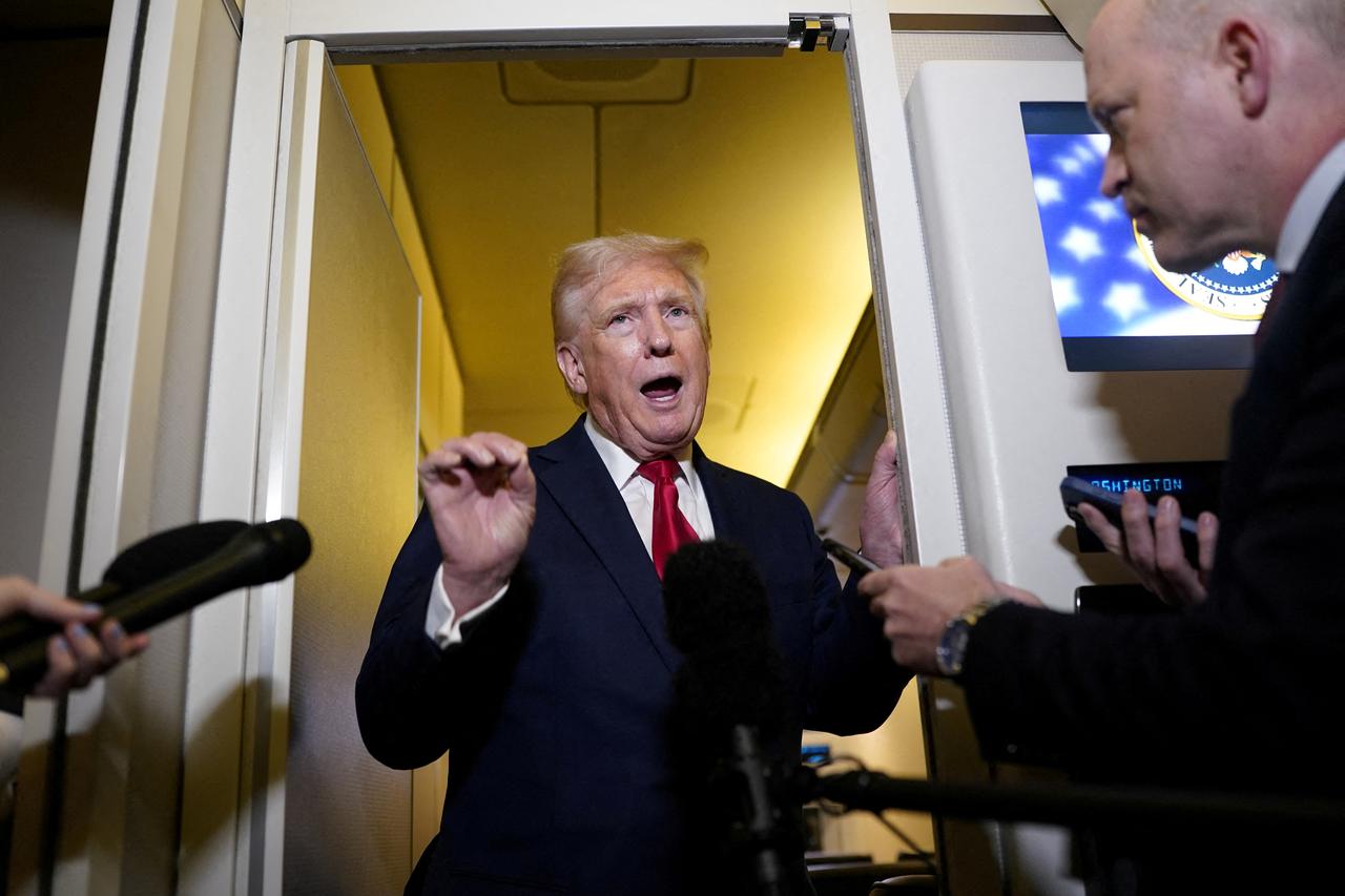 U.S. President Donald Trump speaks to members of the media onboard Air Force One, on a flight to Joint Base Andrews
