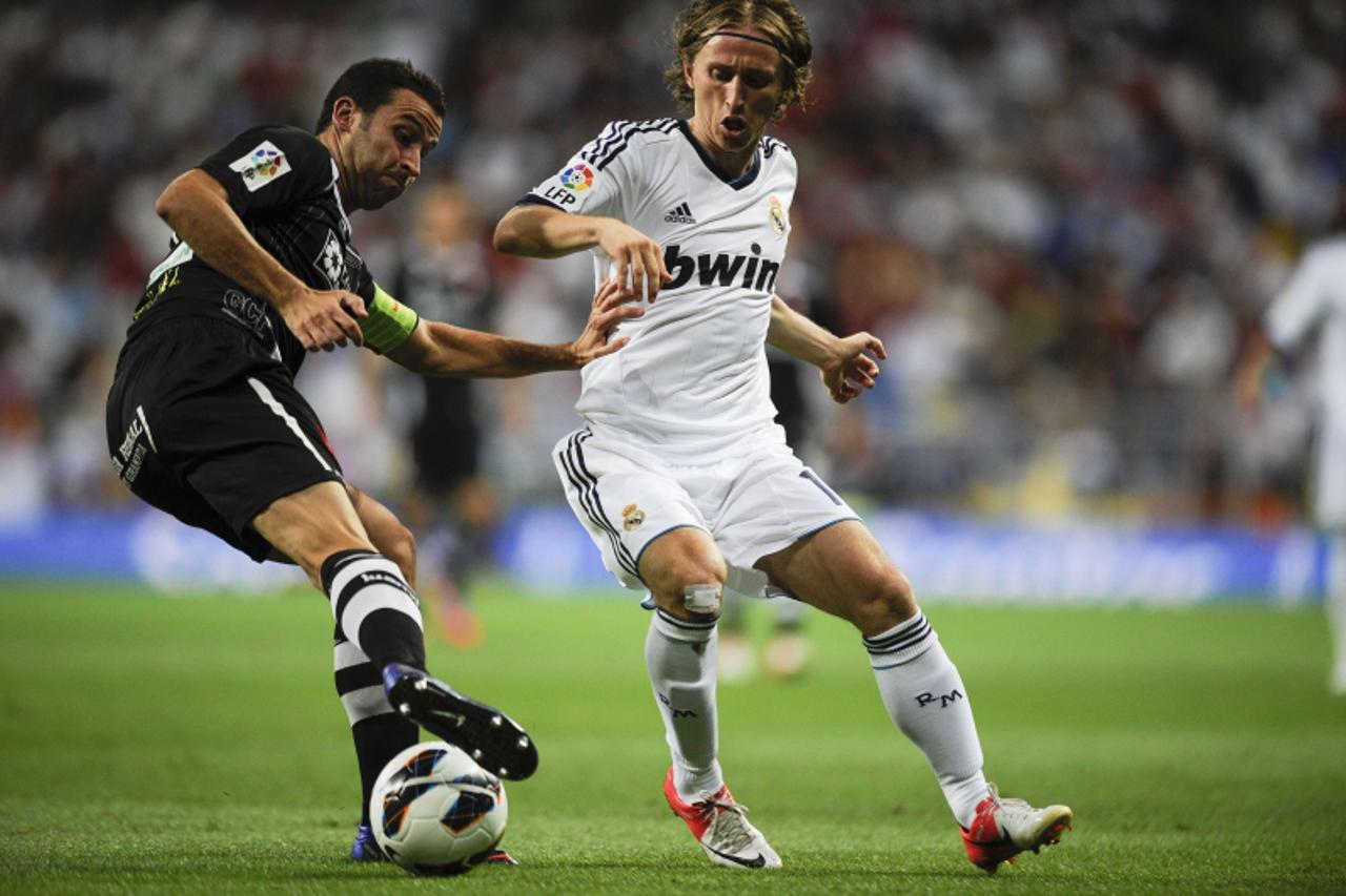 'Real Madrid\'s Croatian midfielder Luka Modric (R ) vies with Granada\'s defender Inigo Lopez (L) during the Spanish League football match  Real madrid vs Granada on September 2, 2012 at the Santiago