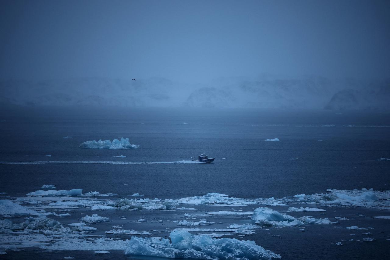 Boat sails near ice blocks floating in the sea during a heavy snowfall near Nuuk