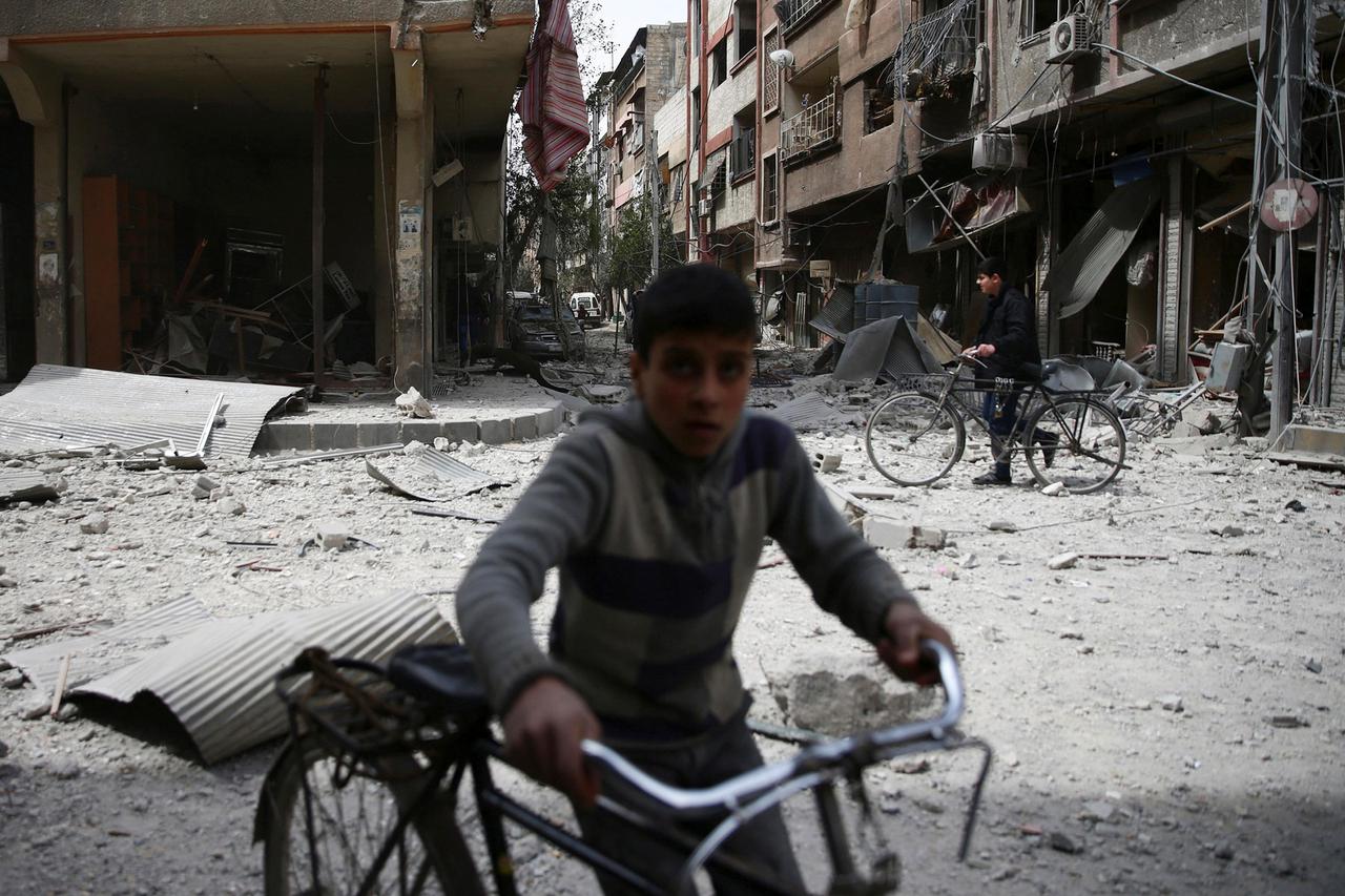 A boy pushes a bicycle at a site hit by an airstrike in the rebel held besieged Douma neighborhood of Damascus, Syria March 27, 2017. REUTERS/Bassam Khabieh