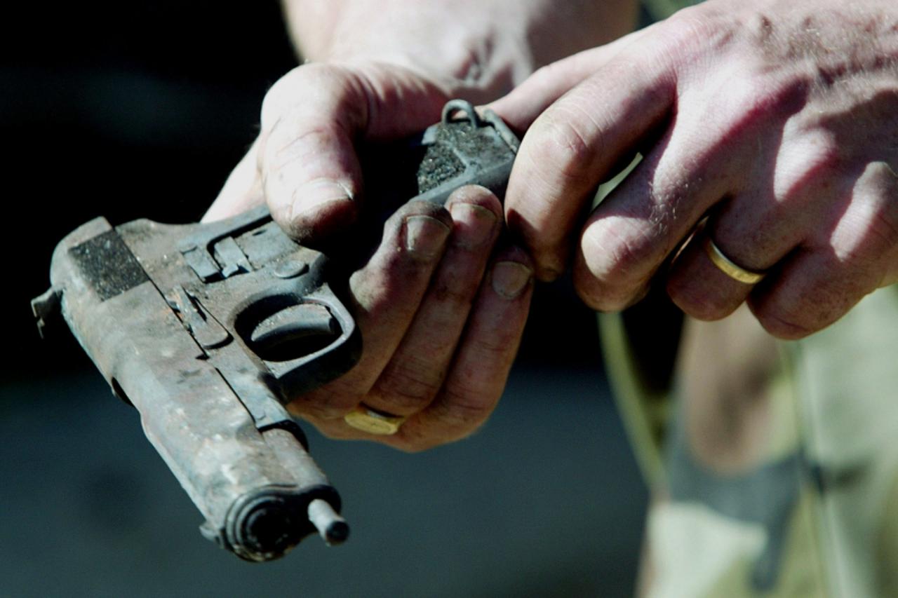 'A British soldier from 33 Engineer Regiment attached to 1st Batallion Royal Gloucesteshire, Berkshire and Wiltshire Regiment, inspects a weapon found in a burnt-out Serb home in Bresje, Kosovo Polje,
