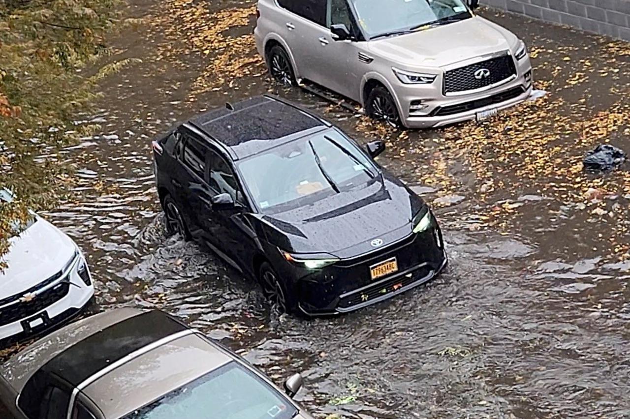 A person drives a car through a flooded street amid rains in New York