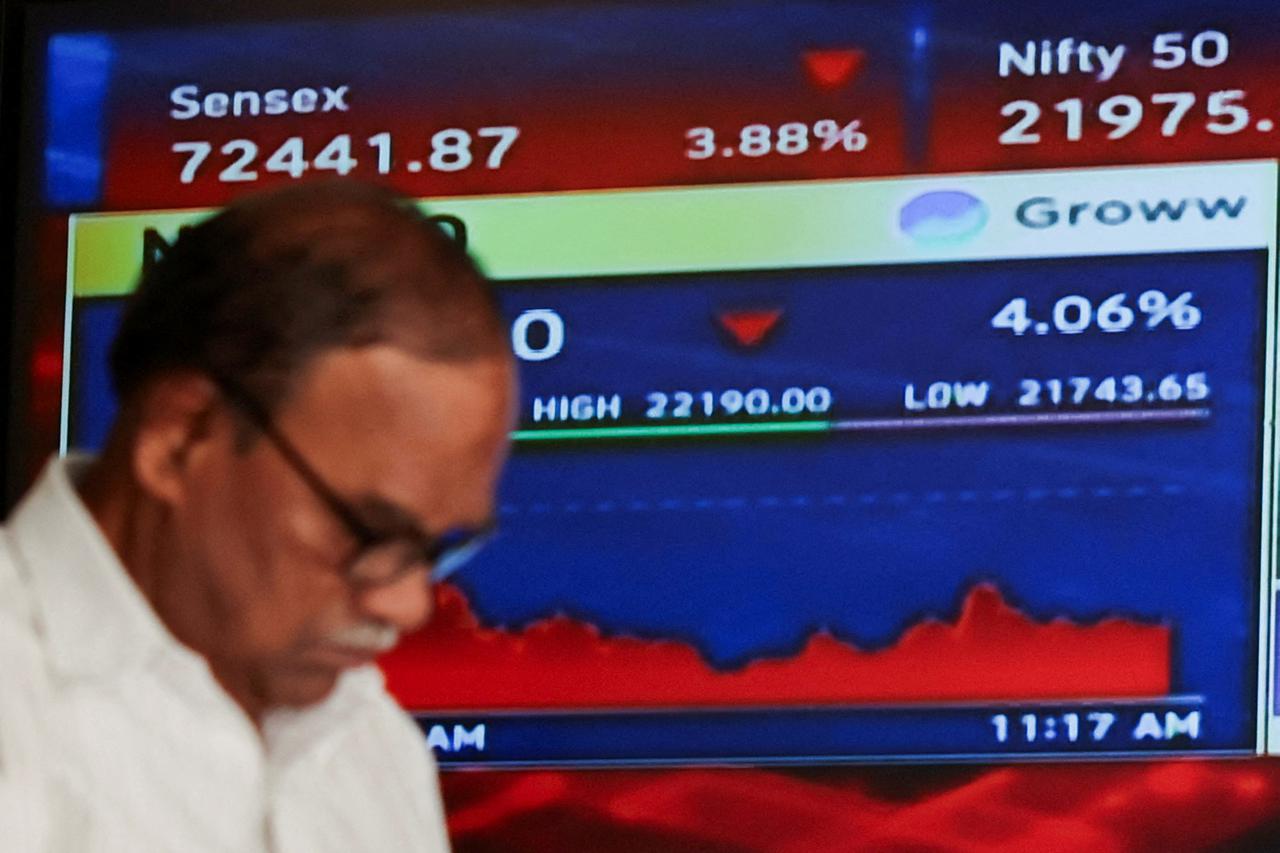 FILE PHOTO: A man walks past a screen displaying market results at the Bombay Stock Exchange (BSE) in Mumbai