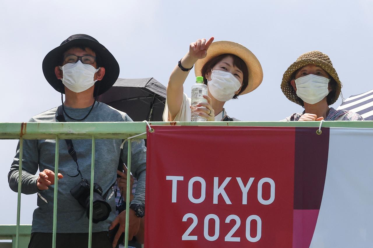 People stand outside the National Stadium before the opening of the Tokyo 2020 Olympic Games in Tokyo