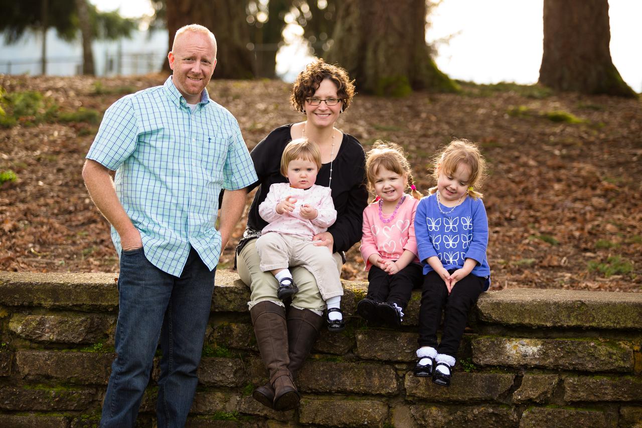 Lifestyle photo of a family of five including mother, father, and three daughters. Two daughters are identical twins.