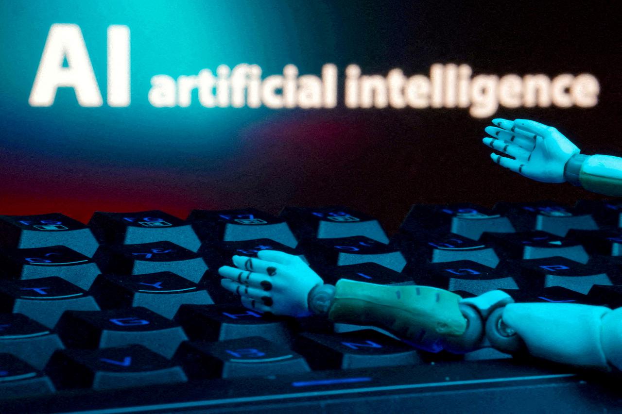 FILE PHOTO: Illustration shows message reading "AI artificial intelligence," keyboard and robot hands
