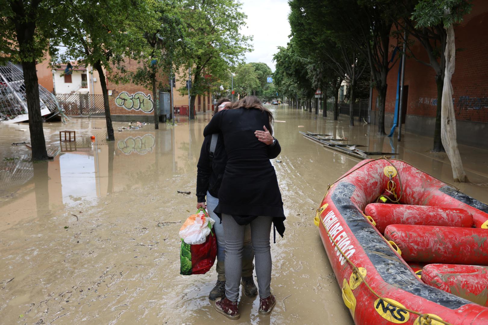 People embrace on a flooded street, after heavy rains hit Italy's Emilia Romagna region, in Faenza, Italy, May 18, 2023. REUTERS/Claudia Greco Photo: CLAUDIA GRECO/REUTERS