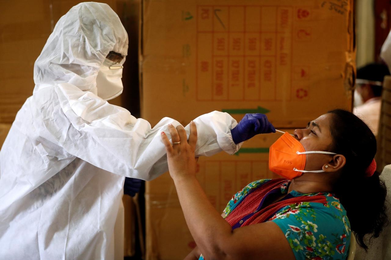 A health worker in personal protective equipment (PPE) collects a swab sample from a woman during a rapid antigen testing campaign for the coronavirus disease (COVID-19), in Mumbai
