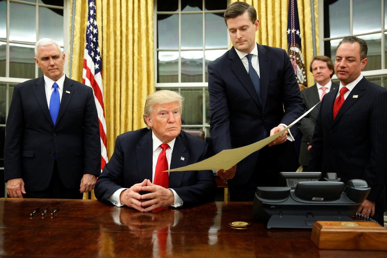 White House Staff Secretary Rob Porter (2nd R) gives U.S. President Donald Trump, flanked by Vice President Mike Pence (L) and Chief of Staff Reince Priebus (R) the document to confirming James Mattis his Secretary of Defense, his first signing in the Ova