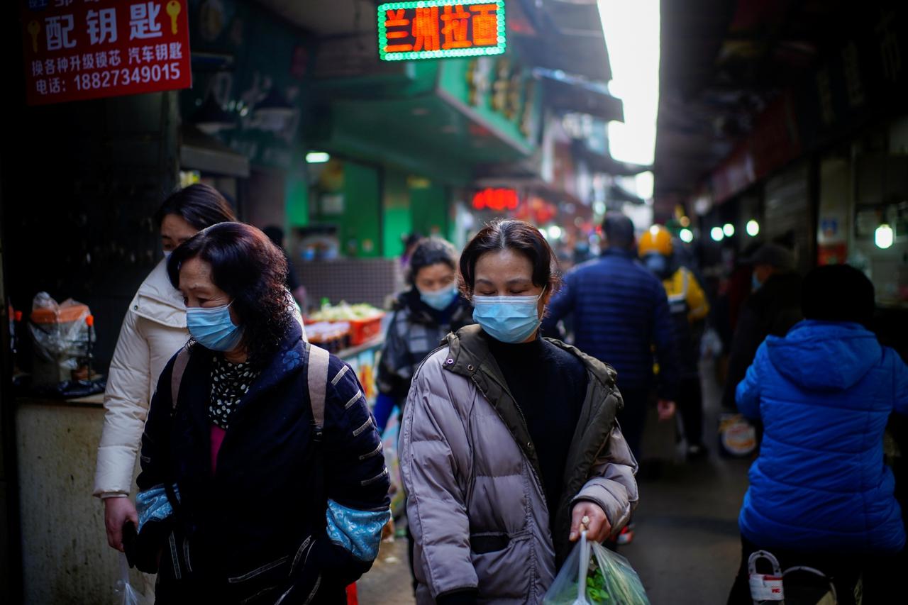 People wearing face masks walk on a street market, following an outbreak of the coronavirus disease (COVID-19) in Wuhan