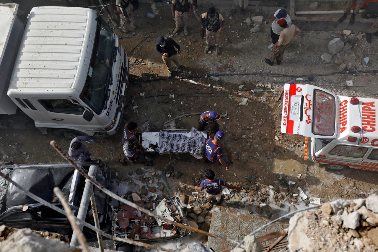 Rescue workers carry a victim at the site of a passenger plane crash in a residential area near an airport in Karachi