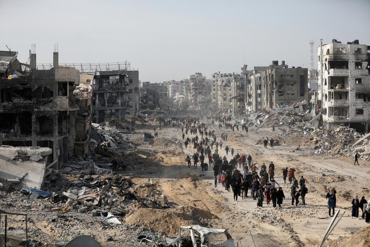 Displaced Palestinians walk past the rubble as they attempt to return to their homes, in the northern Gaza Strip