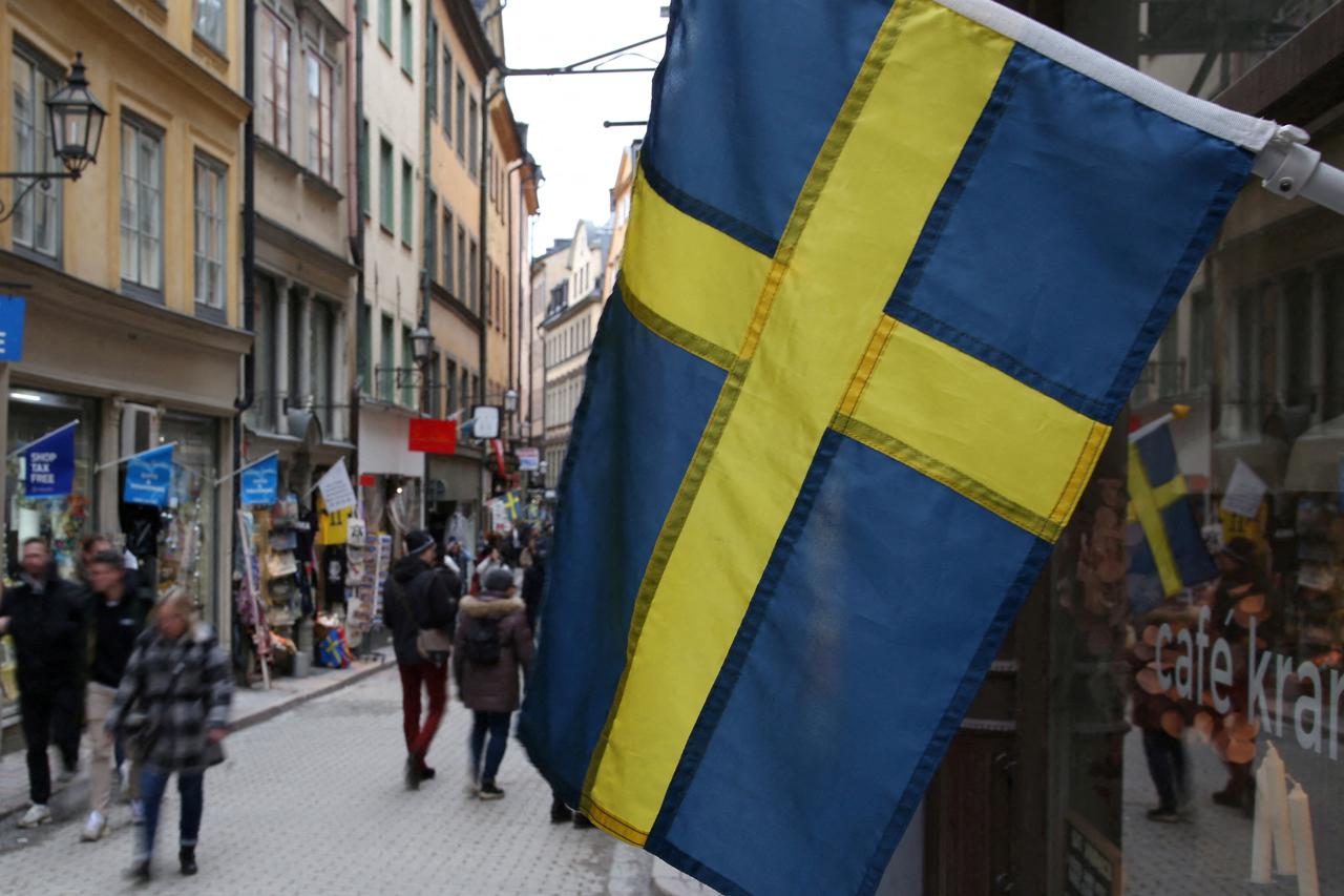 FILE PHOTO: A Swedish flag hangs outside a business on a street of the old city of Stockholm