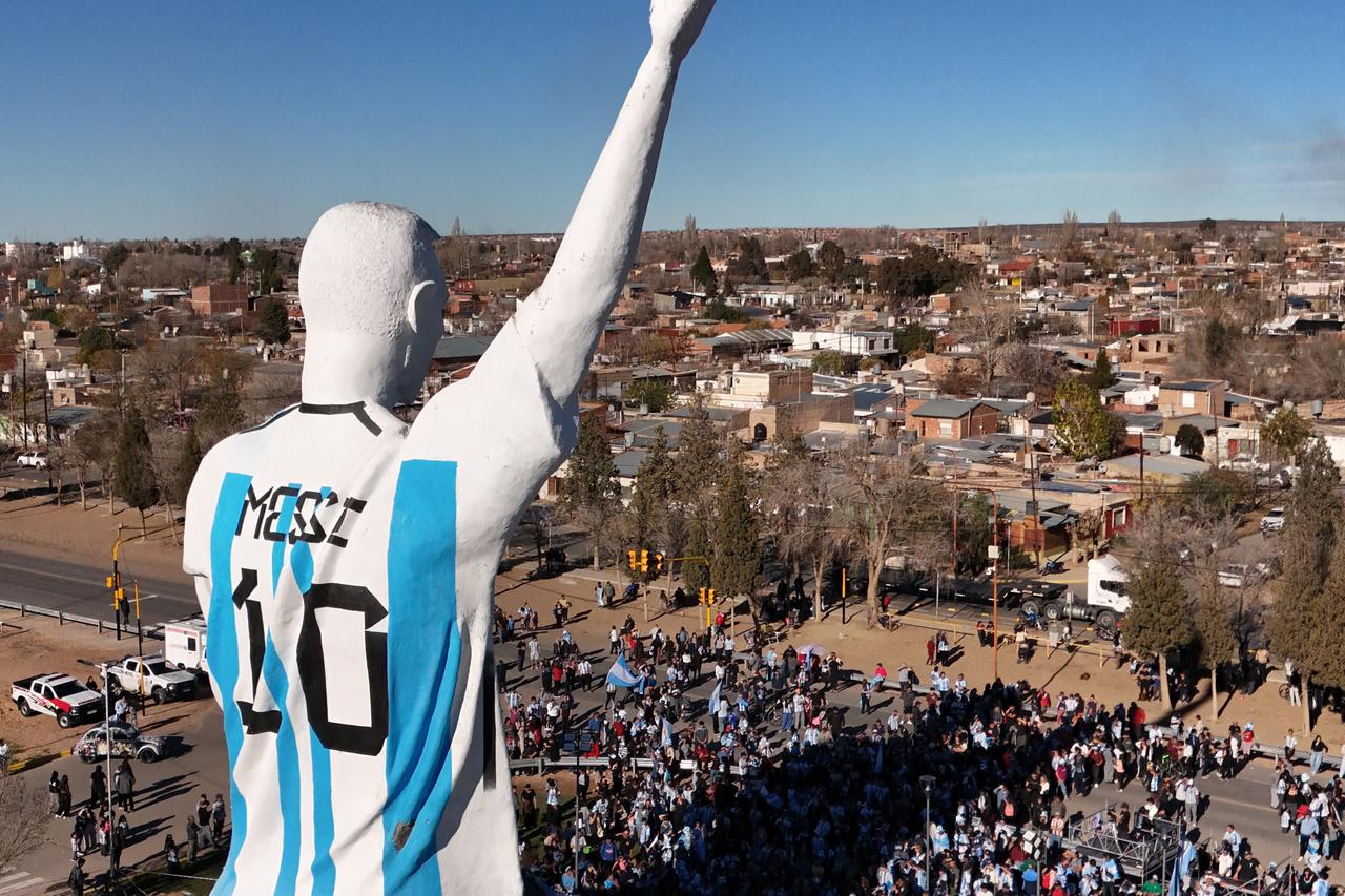 People are gathered near a statue of Lionel Messi in Neuquen Province