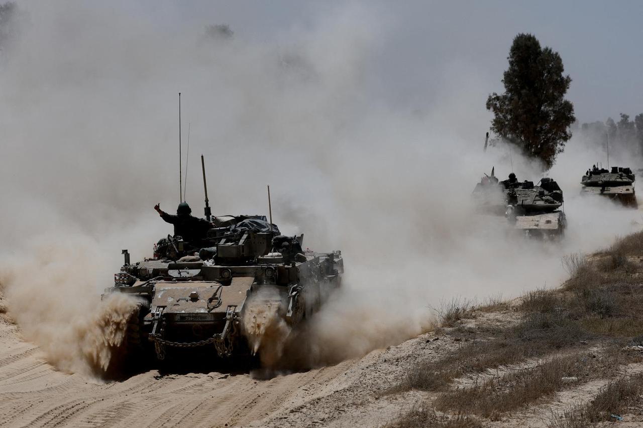 Military vehicles drive their way from the Israeli side of the Israel-Gaza border into Gaza