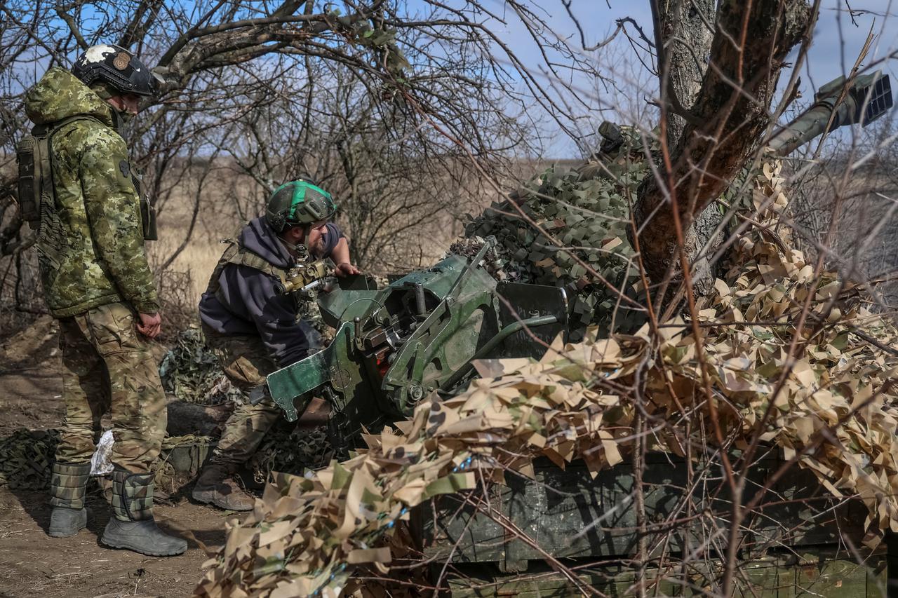 Ukrainian service members fire a towed artillery-piece mortar towards Russian troops near Bakhmut