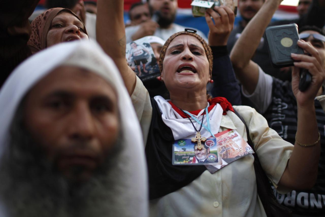 'Fatten, an Egyptian Coptic Christian woman supporter of the Muslim Brotherhood's presidential candidate Mohamed Morsy, holds up a Koran during a rally against the delay of the Egyptian presidential 