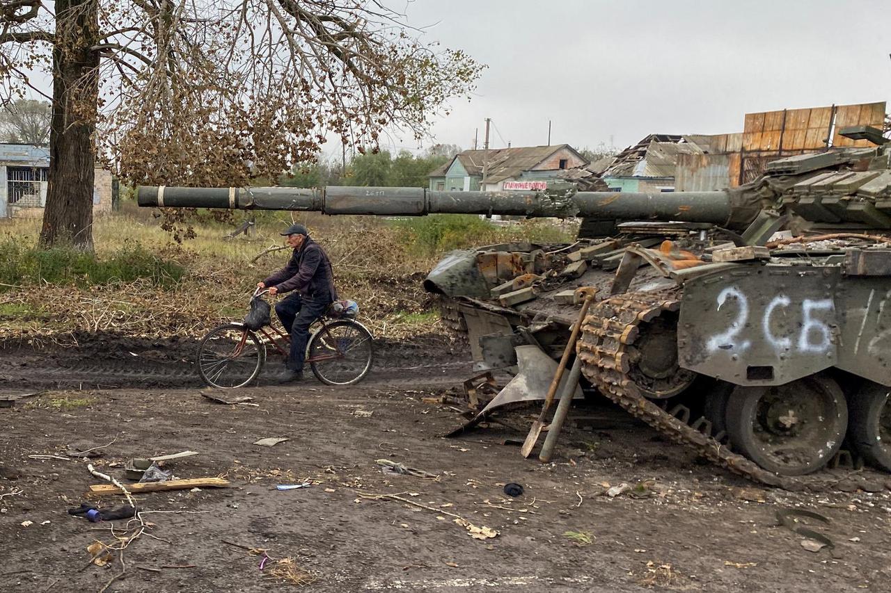 Local resident rides a bicycle past an abandoned Russian tank in the village of Kurylivka