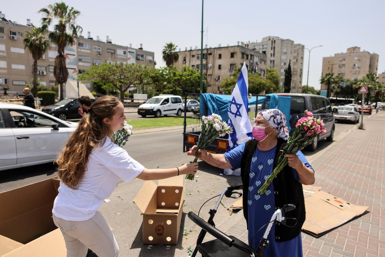 An Israeli woman offers flowers to an elderly by a shopping centre in Ashkelon