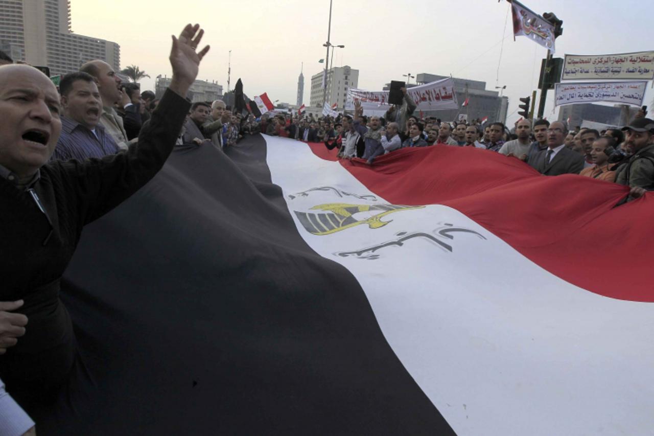 'Anti-Mursi protesters chant anti-government slogans as they carry a large Egyptian flag at Tahrir Square in Cairo November 27, 2012. Opponents of President Mohamed Mursi clashed with Egyptian police 