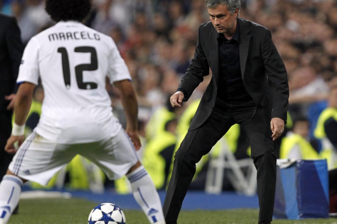 \'Real Madrid\'s coach Jose Mourinho (R) passes the ball through his legs beside his player Marcelo during the first leg of their Champions League quarter-final soccer match against Tottenham Hotspur 