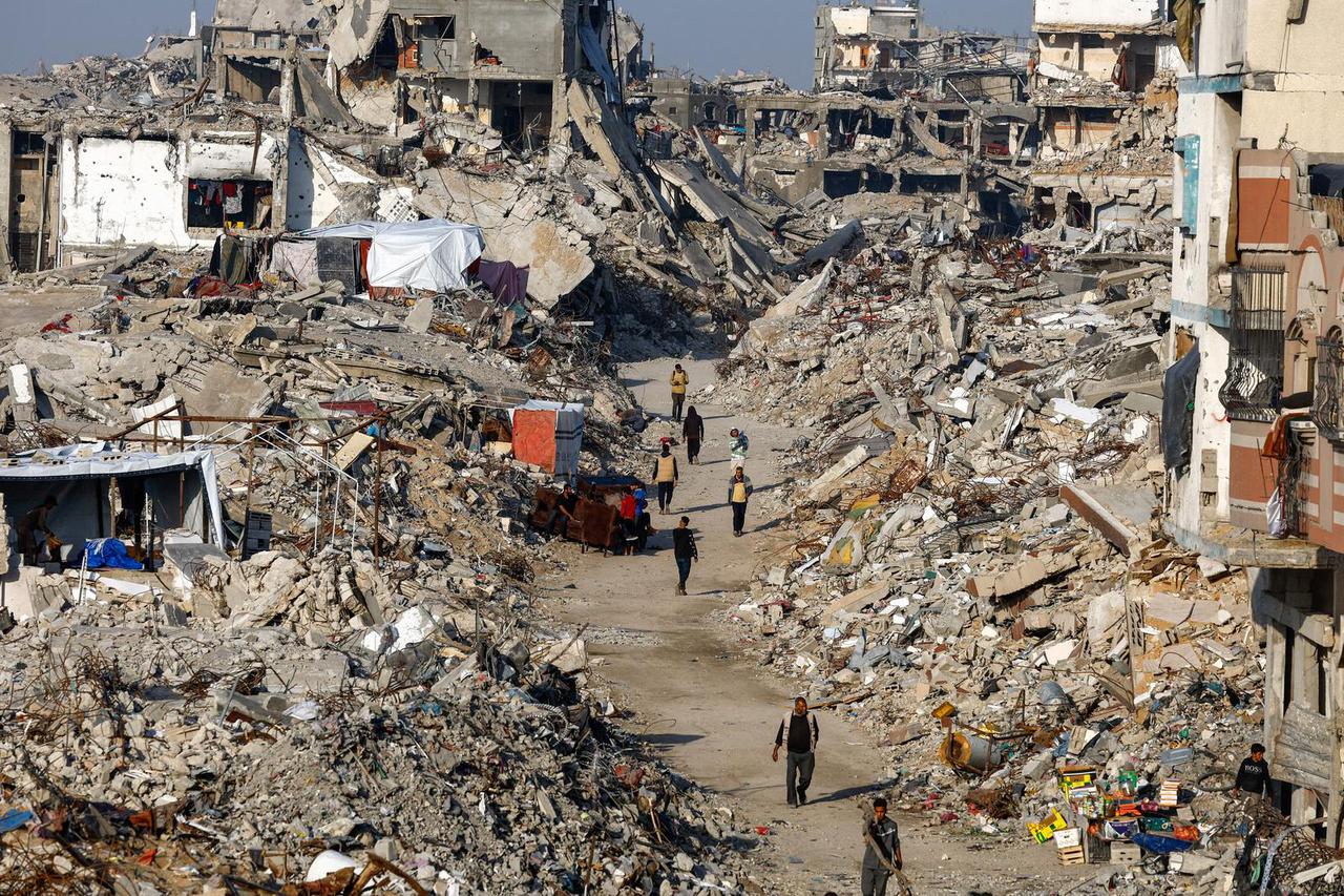 Palestinians walk among piles of rubble, amid a ceasefire between Israel and Hamas, in the northern Gaza Strip