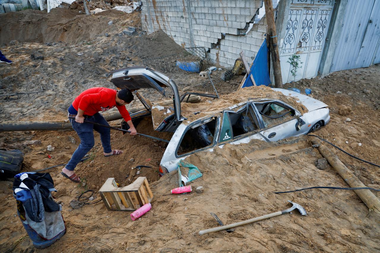 A Palestinian man checks a damaged car